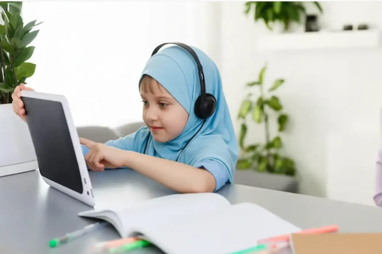 Girl in hijab using a tablet for online Quran learning